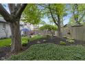 Large, landscaped backyard with mature trees, garden area, grass, and patio furniture under a blue umbrella at 5543 N Pennsylvania N St, Indianapolis, IN 46220