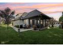 A spacious backyard featuring a screened in porch, lush lawn, and mature trees at 5572 Harness Dr, Greenwood, IN 46143
