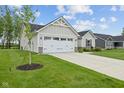 Two-car garage with a concrete driveway and a well-kept lawn adds to the curb appeal of this home at 7051 E Bean Blossom Dr, Camby, IN 46113