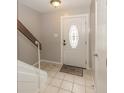 Bright foyer area with neutral tile flooring and a staircase leading to the upper level at 7940 Benjamin Dr, Lawrence, IN 46226