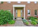 Charming home entrance featuring a bright yellow door with classic columns and beautiful landscaping at 1121 N Cambridge Ct, Greenfield, IN 46140
