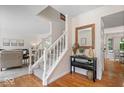 Welcoming foyer with hardwood floors, white staircase, and decorative table with mirror at 11956 Glen Cove Dr, Indianapolis, IN 46236