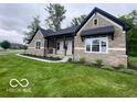 Inviting single-story home with beautiful stone facade, covered entryway, and lush green lawn at 12511 Lowery Way, Fishers, IN 46037
