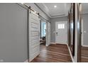 Bright entryway featuring wood-look flooring, sliding barn doors, complemented by modern trim and multiple mirrors at 19348 Mcbee Ave, Westfield, IN 46074