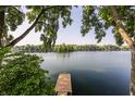 Picturesque lake view with a private dock, surrounded by lush greenery and mature trees at 3585 Bay Rd N Dr, Indianapolis, IN 46240