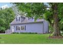 Quaint two-story home with dormer windows framed by a lush green lawn and mature trees at 3713 W 98Th St, Carmel, IN 46032