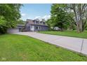 A long driveway leads to a beautiful blue home with green lawns and mature trees at 3713 W 98Th St, Carmel, IN 46032