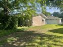 Side exterior view of home with light beige wood paneling and green trees in background at 3908 Bertrand Rd, Indianapolis, IN 46222