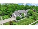 Stunning aerial view showcasing the home's manicured lawn, basketball court, and lush surrounding greenery at 5268 Woodfield Dr N, Carmel, IN 46033