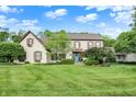 Charming two-story home with brick exterior, blue door, lush landscaping, and a well-manicured lawn at 5268 Woodfield Dr N, Carmel, IN 46033