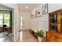 Inviting entryway featuring wainscoting, coat hooks, bench, and a view into a room with large windows at 527 Macintosh Ln, Danville, IN 46122
