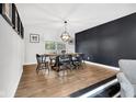 Dining room featuring hardwood floors, modern light fixture, and dark accent wall at 5506 Kessler Blvd N Dr, Indianapolis, IN 46228