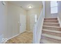 Bright foyer featuring tile flooring, a front door, and staircase to the upper level at 5768 Blue Sky Dr, Whitestown, IN 46075