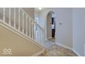 Inviting hallway with staircase, neutral walls, and an arched doorway leading to the kitchen at 5768 Blue Sky Dr, Whitestown, IN 46075