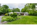 Well-maintained home with lush landscaping, a green lawn, and mature trees at 6455 N Olney St, Indianapolis, IN 46220