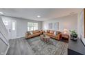Inviting living room with sleek flooring, tan leather sofas, large window, and a decorative rug at 705 Treyburn Lakes Way, Indianapolis, IN 46239