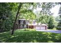 Inviting brick home with a two-car garage nestled amongst mature trees and a green lawn at 7115 Fremont Ct, Indianapolis, IN 46256