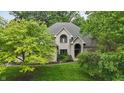 Light brick home with a manicured lawn, mature trees, and arched entryway, providing timeless appeal and elegance at 7138 Nile Ridge Ct, Indianapolis, IN 46236