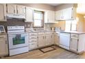 Well lit kitchen with white cabinets, range, dishwasher, sink, and laminate flooring at 8370 State Road 236, North Salem, IN 46165