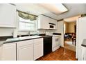 Functional kitchen with white cabinets, black countertops, a sink under the window, and black and white appliances at 1102 Fox Hill Dr, Indianapolis, IN 46228