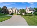 A beautiful stone house with a long driveway lined with landscaping and an American flag flying in the yard at 11101 Hawthorn Rdg, Fishers, IN 46037