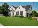 Beautiful white brick home featuring a well-maintained lawn and manicured landscaping at 13218 Beckwith Dr, Carmel, IN 46074