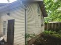 Exterior side view of home with light siding, with lush green trees and partial fence at 1624 E 30Th St, Indianapolis, IN 46218