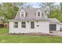 Charming cottage-style home with white siding, dormer windows, green lawn, and attached garage at 2 S 25Th Ave, Beech Grove, IN 46107