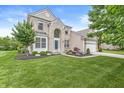 Attractive home with a blend of brick and siding, complemented by a lush green lawn and mature trees at 2070 Mustang Chase Dr, Carmel, IN 46074