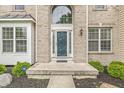 Close-up of the front entrance, showcasing the decorative door, sidelights, and manicured landscaping at 2070 Mustang Chase Dr, Carmel, IN 46074