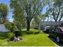 Large backyard with mature trees and a graveled driveway and carport at 2115 S I St, Elwood, IN 46036