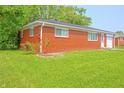 Side of a red brick home with a flower bed and lush green lawn adding to the scenery at 412 S Norfolk St, Indianapolis, IN 46241