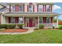 Inviting front porch with white railings, decorative hanging plants, and a welcoming red front door at 4434 W Windsong Ct, New Palestine, IN 46163