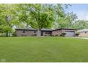 Brick home with an attached garage and a green front lawn shaded by mature trees at 5982 Melbourne Rd, Indianapolis, IN 46228