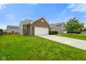 Beautiful brick home with a two-car garage, complemented by a lush green lawn and mature trees at 6415 Calabash Pl, Indianapolis, IN 46217