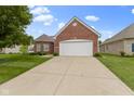 Well-maintained brick home with a manicured lawn, mature tree, and attached two-car garage at 7128 Willow Pond Dr, Noblesville, IN 46062