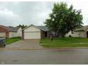 Charming single-Gathering home featuring brick and vinyl siding, a two-car garage, and mature landscaping at 8165 Amarillo Dr, Indianapolis, IN 46237