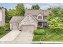 Aerial view of a brick home with a well-maintained lawn, mature trees, and a spacious driveway at 10888 Weston Dr, Carmel, IN 46032