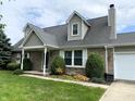 Charming brick home featuring dormer windows, well-manicured lawn and landscaping and a two-car garage at 1135 W Wildflower Ct, Mooresville, IN 46158