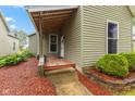 Welcoming front porch with a charming wood deck, stone-lined mulched flower beds and cozy appeal at 1211 W 10Th St, Muncie, IN 47302