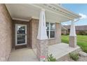 Inviting covered front porch with brick columns and a view of the landscaped yard at 13163 N Departure W Blvd, Camby, IN 46113