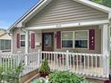 Inviting covered front porch with white railing, red shutters, cozy seating, and well-manicured landscaping at 2612 E Northgate St, Indianapolis, IN 46220