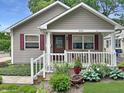 Close-up of front exterior with a cozy porch, white railing, red shutters, and beautifully landscaped garden at 2612 E Northgate St, Indianapolis, IN 46220