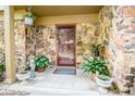 Inviting front porch with stone accents, potted plants, and a hanging basket with flowers at 3935 Offshore Dr, Columbus, IN 47203