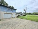 Spacious driveway with basketball hoop leading to a well-maintained white brick home with attached two-car garage at 404 E Madison St, Alexandria, IN 46001