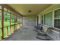 Enclosed porch with seating, providing a cozy outdoor space with views of the well-manicured lawn and garden at 4125 S Post Rd, Indianapolis, IN 46239