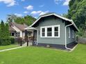 Cozy home with gray siding, white trim, a cozy front porch and lush green lawn at 4345 Guilford Ave, Indianapolis, IN 46205