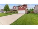 Well-maintained concrete driveway leading to a home with red siding and brick accents at 4683 W Lawrence Way, New Palestine, IN 46163