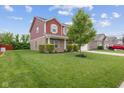 Inviting front yard with lush green grass and mature tree, complementing the charming red home at 4683 W Lawrence Way, New Palestine, IN 46163