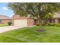 Beautiful brick home featuring a lush green lawn, mature trees, and a cozy front entryway at 4725 W Harrisburg Ct, New Palestine, IN 46163